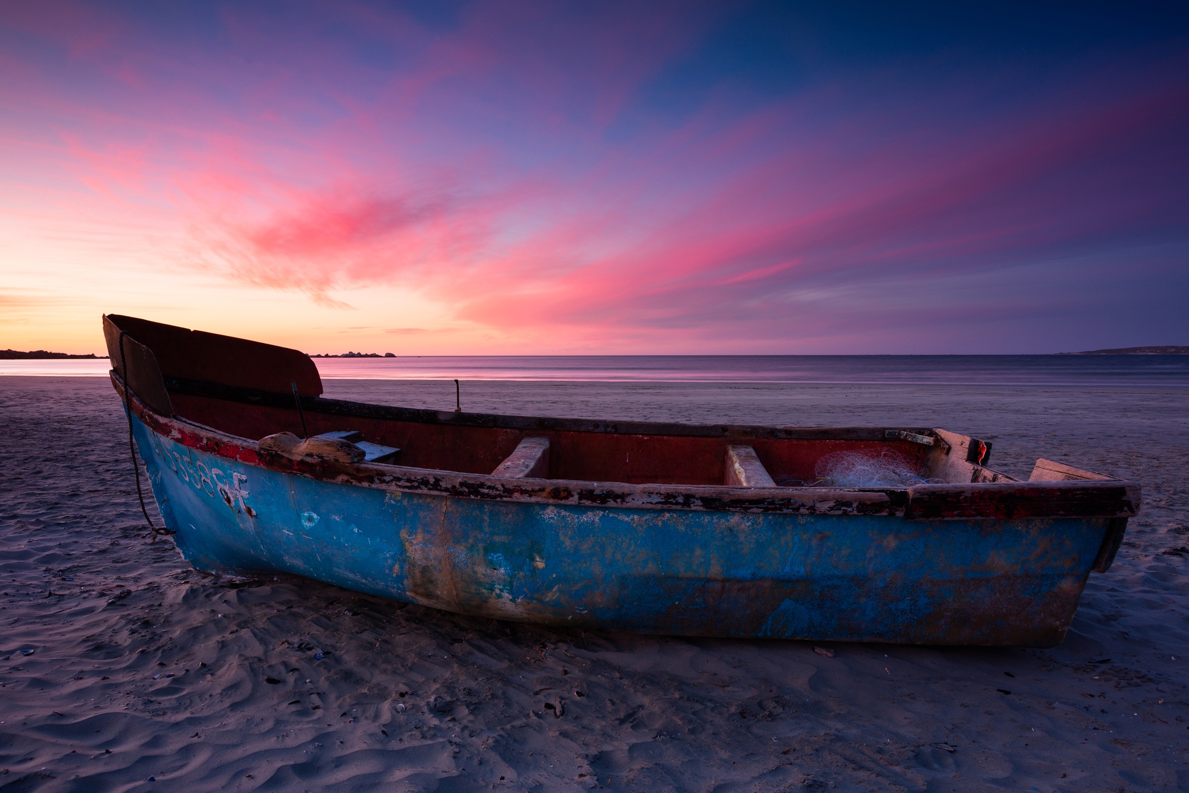 A traditional fishing boat on Paternoster beach beneath a vivid West Coast sunset.